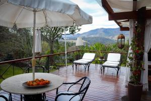 a deck with chairs and tables and an umbrella at Pousada Vidinha Bela in Brazópolis