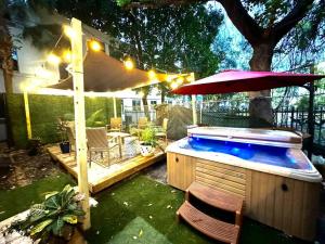 a hot tub in a backyard with a umbrella at Brickell + Wynwood Wonderland: Spacious 6BR Home in Miami
