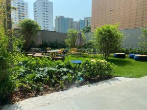 a garden with plants and tables and buildings at For You Moema 302 Studio da Andrea in São Paulo
