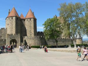 a group of people walking in front of a castle at La petite chambre du lac in Carcassonne