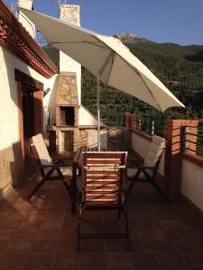 una mesa y sillas bajo una sombrilla en el balcón en Cortijo los Bataneros, en Segura de la Sierra