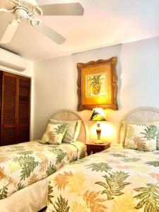 ein Schlafzimmer mit 2 Betten und einem Tisch mit einer Lampe in der Unterkunft Poipu Crater 14 Peaceful Beach Retreat with AC in Koloa