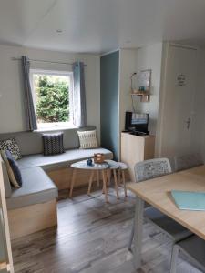 a living room with a couch and a table at Mobil-home La perle bleue in Ouistreham