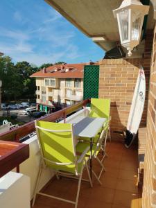 een balkon met stoelen, een tafel en een surfplank bij Apartamento a 30 metros de la playa in San Vicente de la Barquera