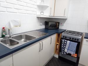 Il comprend une petite cuisine équipée d'un évier et d'une cuisinière. dans l'établissement Beautiful 2-Bed House in Bolton with free parking, à Bolton