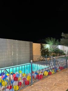 a pool with colorful beach umbrellas in front of a fence at شالية السحاب in Al Ḩazm