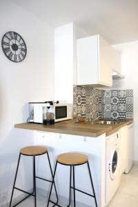 a kitchen with white cabinets and two stools at Studio cosy front de mer à 5min de Nice in Saint-Laurent-du-Var