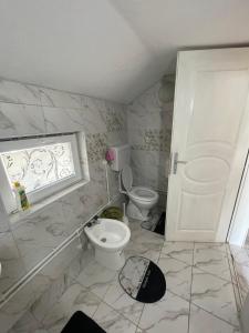 een witte badkamer met een toilet en een raam bij Marko Konak in Niš