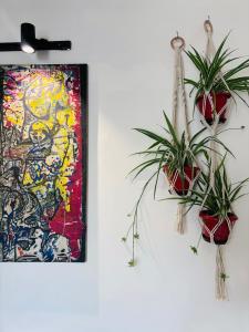 two potted plants on a wall next to a painting at Anavrin Art House in New Delhi