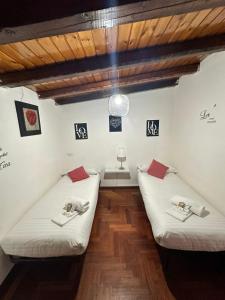 two beds in a room with wooden floors at R Home in Catania