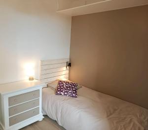 - une chambre avec un lit et une table de chevet avec un oreiller dans l'établissement La porte de Paris, à Rosny-sous-Bois