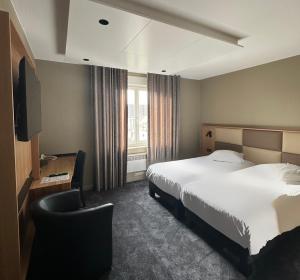 une chambre d'hôtel avec un lit et une chaise dans l'établissement Hotel Au Nid De Cigognes, à Ostheim