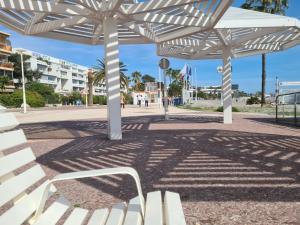 a group of white benches under a white umbrella at Studio cosy front de mer à 5min de Nice in Saint-Laurent-du-Var