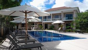 a pool with chairs and umbrellas next to a building at ISLA HOLIDAY HOME in Anse Royale