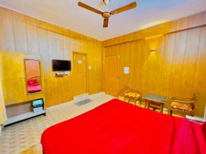 a bedroom with a red bed and a ceiling fan at Grand view lodge and Restaurant Dharamshala - Partial Prepayment required to confirm booking in Dharamshala