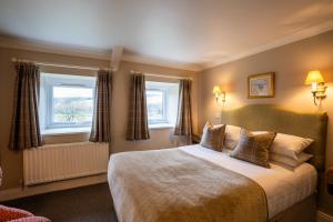 a bedroom with a large bed and two windows at The Pheasant Inn in Falstone