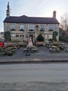 a building with picnic tables in front of it at Peak District - 1 Harrow Cottage - Great Longstone in Great Longstone