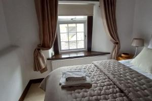a bedroom with a bed and a window at Peak District - 1 Harrow Cottage - Great Longstone in Great Longstone