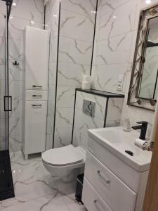 a white bathroom with a toilet and a sink at Apartament Klimatyzowany na Ciepłej in Białystok