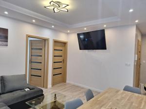 a living room with a table and a tv on the wall at Apartament Klimatyzowany na Ciepłej in Białystok +7 photos
