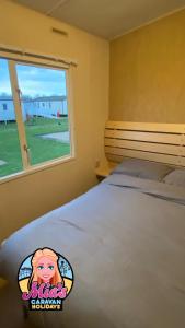 a bedroom with a large bed with a window at The Atlas Everglade Caravan in Ingoldmells