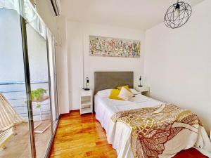 a white bedroom with a bed and a large window at Romántico apartamento en el corazón de Palermo. in Buenos Aires