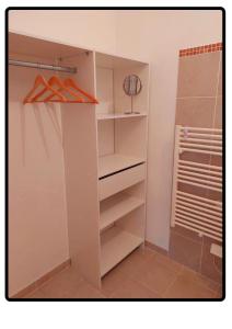 a walk in closet with white cabinets and hangers at Appartement Roussillon in Roussillon