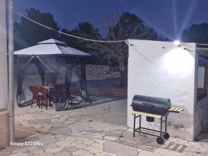 a grill on a stand next to a table and an umbrella at Casa Rural Natur Libre in Alicante