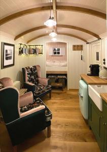 a kitchen with two chairs and a living room with a couch at The Garden Hut Cilcain in Mold