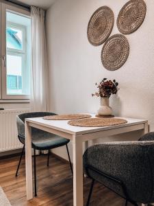 una mesa blanca con sillas y un jarrón con flores en Ferienwohnung Sonnenhof, en Niederstotzingen