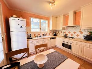 uma cozinha com armários brancos e um frigorífico branco em Villa Tournesol - Maisons & Villas pour 8 Personnes 271 em La Grande-Motte