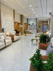 un vestíbulo con muebles blancos y plantas en un edificio en Bahget Eljouf Furnished Apartment en Aţ Ţuwayr