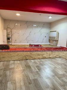 una camera con un grande letto rosso e una parete in marmo di Bahget Eljouf Furnished Apartment a Aţ Ţuwayr