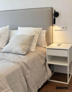 uma cama com uma mesa de cabeceira branca ao lado de uma cama branca sidx sidx em DATERRA 20 em Póvoa do Caraminhal