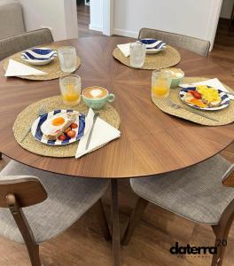 a wooden table with plates of breakfast foods and glasses of orange juice at DATERRA 20 in Pobra do Caramiñal