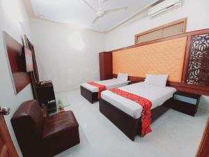 una habitación de hotel con 2 camas y una silla en Rose Palace Guest House en Karachi