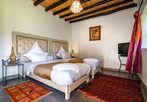 a bedroom with two beds and a television in it at Kasbah Alili in Marrakesh