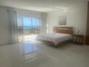 Villa Ferreira Punta Rucia near Ensenada beach في بونتا روسيا: غرفة نوم بيضاء مع سرير ونافذة كبيرة