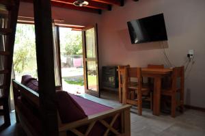 sala de estar con mesa y TV en la pared en Cabaña en Villa Los Coihues en San Carlos de Bariloche