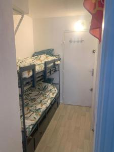 Una pequeña habitación con dos literas y una puerta. en Joli studio proche plage du Môle, en Cap d'Agde