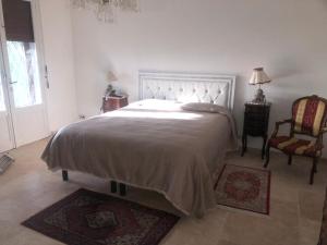 a bedroom with a large bed and a chair at Villa avec piscine au soleil de la côte d’azur in Mouans-Sartoux