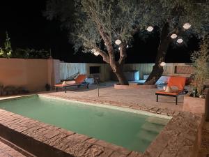 a swimming pool in a backyard at night at Hôte sahara & spa TADIGHOUST in El Hara