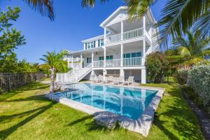 a large white house with a swimming pool in front of it at Sophisticated Sunsets by Brightwild-Pool & Dock! in Key West