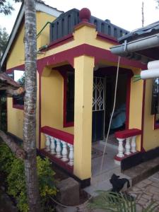 una pequeña casa amarilla y roja con porche en Stay with Daktari Homes, en Homa Bay