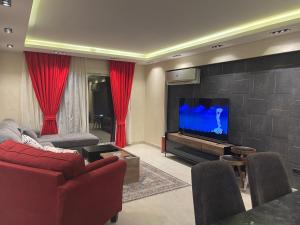sala de estar con sofá rojo y TV de pantalla plana en ArabElite, en El Cairo