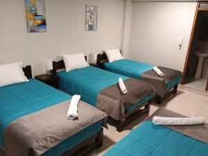 drie bedden in een kamer met blauwe lakens bij Vianca Hotel in Machu Picchu