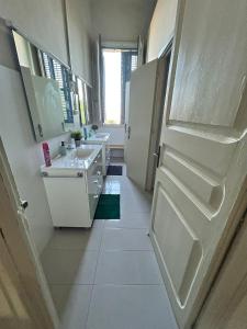 a white bathroom with two sinks and a refrigerator at Casa Mariel in El Masnou