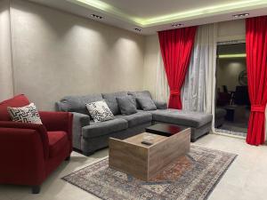 sala de estar con sofá y cortinas rojas en ArabElite, en El Cairo