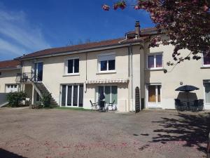a large white house with chairs and an umbrella at Appartement à Limoges in Limoges