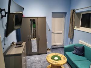 een woonkamer met een groene bank en een televisie bij No.11 in Llannon